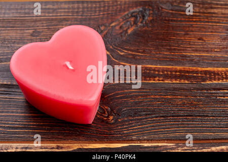 Naturale a forma di cuore candela rossa. La cera a forma di cuore sulla candela in legno marrone e sfondo spazio copia. Elemento per vacanze San Valentino design romantico. Foto Stock