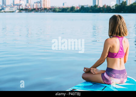 Donna fare yoga sulla scheda del pannello SUP Foto Stock