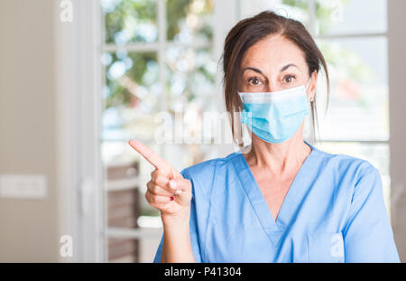 Persone di mezza età medico donna molto felice puntando con mani e dita Foto Stock