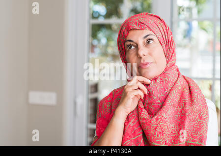 Di mezza età della donna musulmana che indossa il hijab faccia seriamente pensando di domanda, molto confusa idea Foto Stock