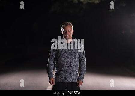 Senior sani runner in fase di riscaldamento e stretching nel parco della città prima della formazione di notte Foto Stock