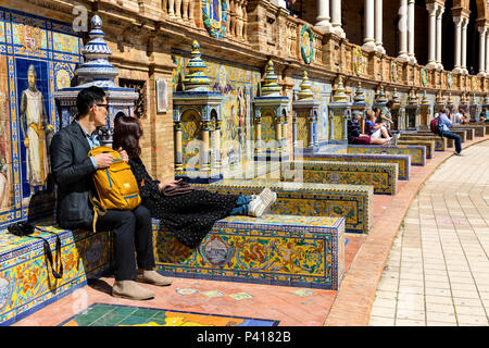 I turisti di relax al sole sulla provincia piastrellato alcove, Plaza de Espana, Andalusia, Spagna. Foto Stock