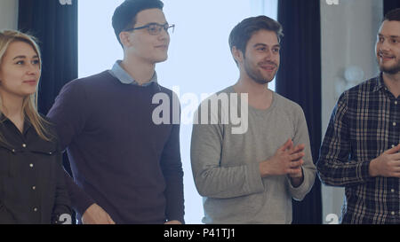 Un gruppo di persone in piedi nella parte anteriore del business coach, di ascolto e di discutere di una presentazione Foto Stock