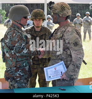 Il polacco Brig. Gen. Dariusz Gorniak, il comandante polacca della decima brigata meccanizzata e il Land di comandante delle forze a Drawsko Pomorskie per Anakonda 16, guarda come Col. Phil Brooks, il comandante per 1° Brigata corazzate contro la squadra, terza divisione di fanteria, scuote le mani con un soldato dalla ex Repubblica iugoslava di Macedonia dopo la firma della accordo di autorità segnando l inizio ufficiale dell'esercizio Anakonda 16 a Drawsko Pomorskie, Polonia il 6 giugno. Foto Stock