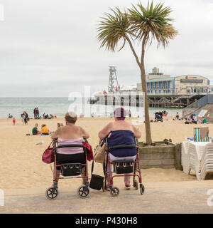 Due anziani donna seduta nella mobilità sedie che si affaccia su una spiaggia Foto Stock