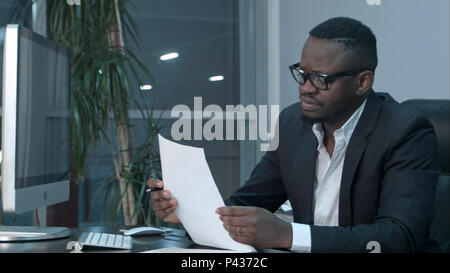 Imprenditore africano facendo lavori di carta, il calcolo di finanziare le fatture in ufficio Foto Stock