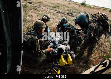 Sgt. Jamie Fox (a destra), un combattimento Medic assegnato alla società C., 2° Battaglione, 227th reggimento di aviazione, 1° aria brigata di cavalleria guide soldati polacchi verso dopo la risposta a un nove-line medevac durante l'esercizio Anakonda 2016 (un16) a Miroslawiec Air Base, Polonia, 11 giugno 2016. Un16 un polacco-led, multinazionale di evento di formazione in funzione da giugno 7-17, coinvolge circa 31.000 partecipanti provenienti da più di 20 nazioni ed è il principale evento di formazione per gli Stati Uniti Esercito europeo. Foto Stock