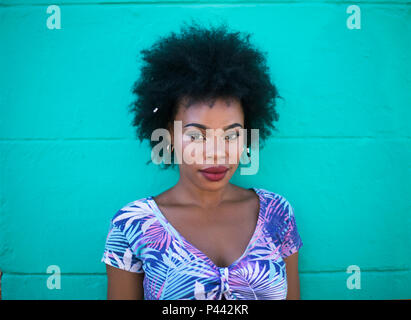 Un modello di africani si erge contro un turchese dipinto di parete in calcestruzzo Foto Stock