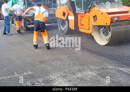 Operai della costruzione su di asfaltatura della strada e la riparazione Foto Stock