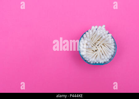 Tamponi di cotone nel vaso in plastica su sfondo rosa. Uso singola tamponi in plastica bandito da alcuni paesi per la riduzione dell'inquinamento. Concetto foto. Foto Stock