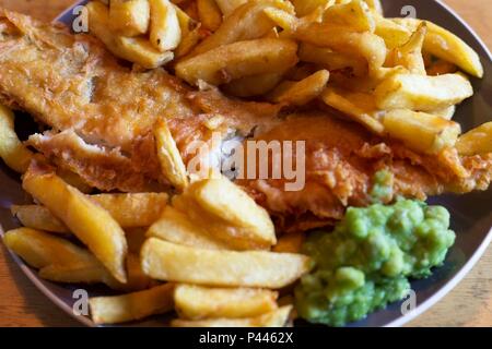 Pesce e patatine, un tradizionale pasto inglese costituito da fritte di merluzzo e patatine con fiacco piselli Foto Stock