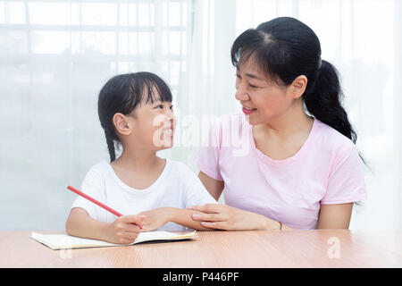 Asian madre cinese insegnamento figlia a fare i compiti a casa Foto Stock