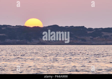 Sun nascondersi dietro la linea costiera di Caló de s'Oli e Can Marroig al tramonto dalla Sa Boca nel Parco Naturale di Ses Salines(Formentera,Isole Baleari, Spagna) Foto Stock