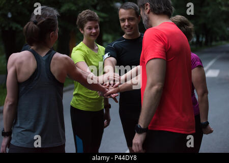 Gruppo di corridori sani dando alta cinque per ogni altro mentre celebriamo il successo dopo una sessione di formazione. Foto Stock