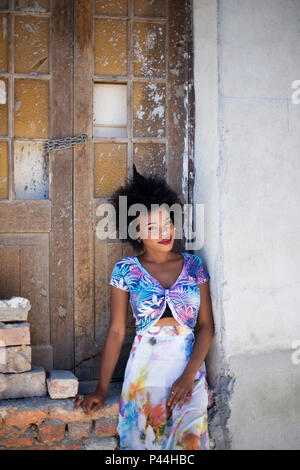 Un modello di africani si siede su un vecchio muro di pietra e porte in legno Foto Stock