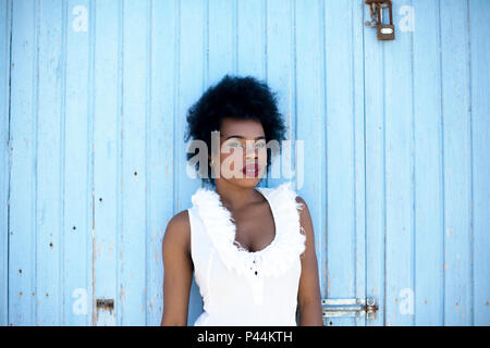 Un giovane africano modello si appoggia contro un baby blue porte dipinte Foto Stock