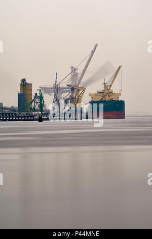 Contenitore nave ormeggiata nel porto di Amsterdam venga scaricato da enormi gru sulla riva Foto Stock