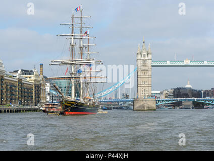 Un alto veliero mored sulla riva sud del fiume Tamigi vicino al Tower Bridge, Vittoriano costruito a bilico e sospensione ponte per pedoni Foto Stock