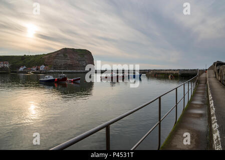 Bella serata di maggio nel pittoresco villaggio di Staithes, North Yorkshire. Il sole che tramonta in un cielo di cloud alta al di sopra del porto. Foto Stock