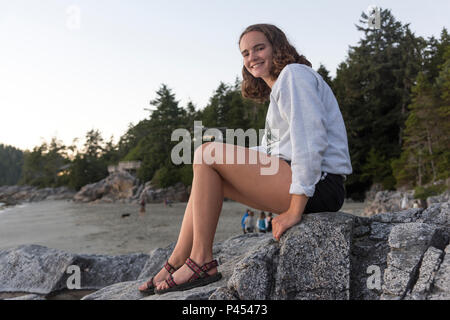 Donna seduta su una roccia, Tonquin Beach, Tofino, Isola di Vancouver, British Columbia, Canada Foto Stock