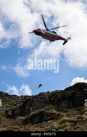 HM Coastguard Bristow di ricerca e salvataggio in elicottero 936 winchman abbassamento in bilico durante una montagna operazione di salvataggio su Moel Siabod Snowdonia Wales UK Foto Stock