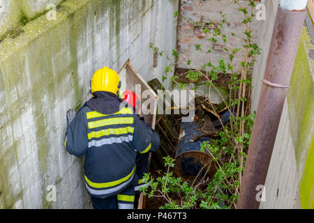 Vista da dietro il vigile del fuoco in uniforme sta andando giù per la scala. Foto Stock