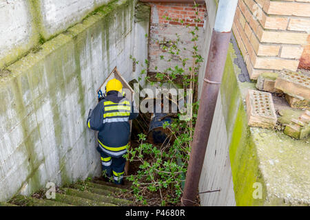 Vista da dietro il vigile del fuoco in uniforme sta andando giù per la scala. Foto Stock