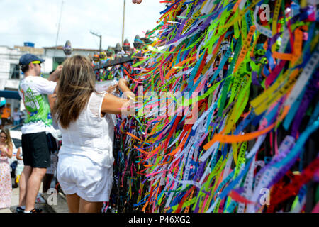 SALVADOR, BA - 26/12/2014: ÚLTIMA SEXTA-FEIRA DO ANO EM SALVADOR - (Amarrando fitinha do Bonfim e fazendo pedidos. Tradição nos gradis da igreja) Na última Sexta-feira do ano, em Salvador, fiéis sobem una colina Sagrada para pedir bençãos e agradecer ao Senhor do Bonfim, na Igreja do Bonfim. Para os devotos fare candomblé una sexta-feira é o dia dedicado ao orixá Oxalá, que no sincretismo é o Senhor do Bonfim - Gesù. Neste dia, veste-se o branco em reverência ao pai maior dos Orixás, Oxalá. Várias missas campais são celebradas duranti o dia, desde come cinco da manhã. Em frente a igreja, há também come Foto Stock