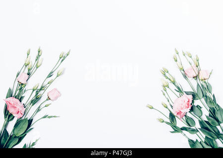 Piatto floreale disposizione laici con fiori di colore rosa su sfondo bianco. Telaio realizzato in due eustoma bouquet di rose con centro vuoto, vista dall'alto. Foto Stock