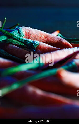 Vista laterale di un gruppo di piccole ROSSO PEPERONCINO congelati in una cucina in attesa di essere cotti Foto Stock