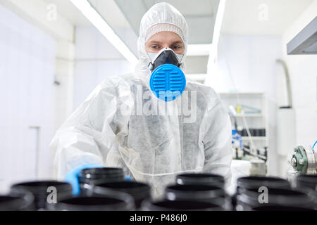 Operaio di fabbrica nel respiratore tenendo il contenitore nero Foto Stock