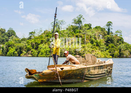 Due uomini locali, persone illegalmente la sabbia di scavo utilizzando una fatiscente barca da fiume Madu, Madu Ganga zone umide, sud-occidentale dello Sri Lanka Foto Stock