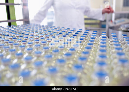 Riempimento e produzione di farmaci in un prodotto farmaceutico nastro trasportatore con bottiglie e un lavoratore Foto Stock