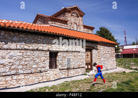 Ohrid, Repubblica di Macedonia : un bambino in un costume di Spiderman passeggiate passato la Santa Madre di Dio Peribleptos chiesa (1295), una delle più antiche chiese Foto Stock