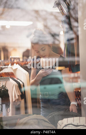 Bella donna utilizzando il telefono cellulare mentre lo shopping Foto Stock