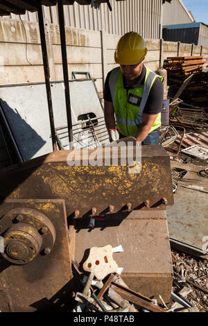 Lavoratore lavora in scrapyard Foto Stock