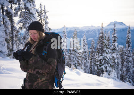 Donna in abiti invernali Riesame di foto sulla fotocamera digitale Foto Stock