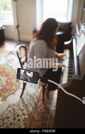 Bellissima femmina vlogger suonando piano Foto Stock
