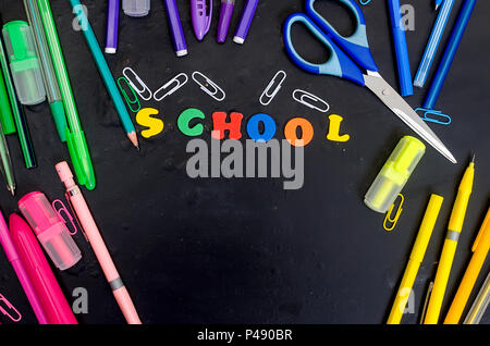 Lay piatto con caratteri di ritorno a scuola e una serie di attrezzature scolastiche sulla lavagna Foto Stock