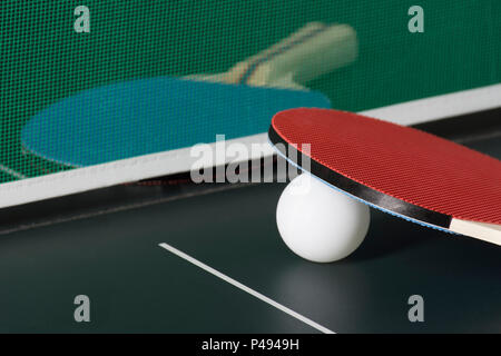 Ping Pong le piastre su un tavolo da Ping Pong che mostra la net, una racchetta al di fuori della messa a fuoco in background. Foto Stock