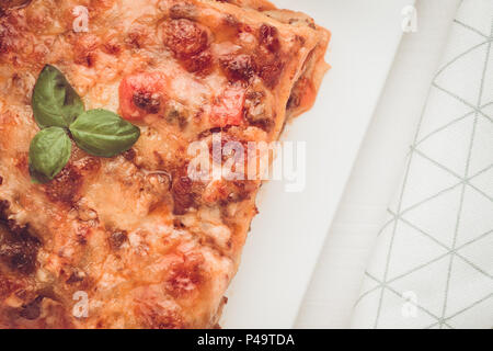 Lasagne fatte in casa con la carne macinata, la salsa di pomodoro e basilico fresco sulla piastra bianca Foto Stock