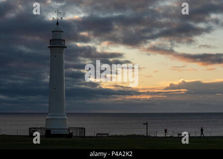 Sunderland, Regno Unito. Il 21 giugno, 2018. Solstizio d'estate sunrise. Una bella mattina nel Regno Unito, il meteo è calma per ora. Una mattina presto corre pareggiatore verso Seaburns del XIX secolo il faro in Cliffe park sopra Roker spiaggia mentre il sole tenta di rompere attraverso le nuvole. Credito: Dan Cooke/Alamy Live News Foto Stock