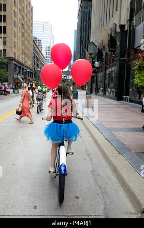 In costume di equitazione donna la sua bicicletta con tre palloncini rossi in Tour de Fat sfilata attraverso il centro cittadino di Minneapolis. Minneapolis Minnesota MN USA Foto Stock