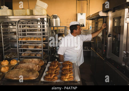 Il panettiere di sesso maschile che lavorano in baker shop Foto Stock