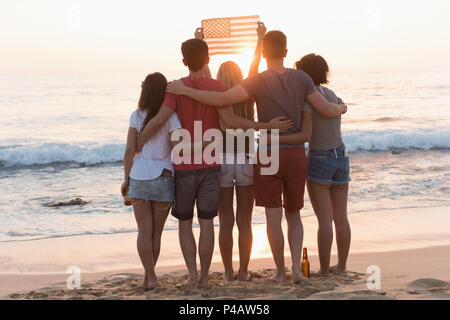 Gruppo di amici holding bandiera americana in spiaggia Foto Stock