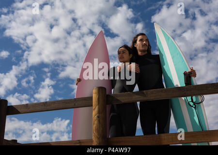 Surfer giovane in piedi con la tavola da surf in spiaggia Foto Stock