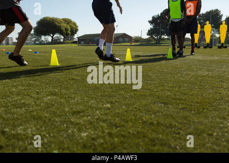 I giocatori di calcio dribbling la sfera attraverso coni Foto Stock