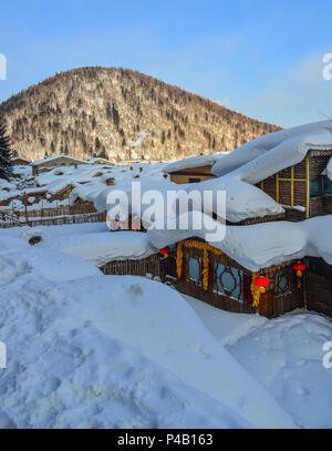 Case di legno coperto di neve al villaggio di montagna a Harbin, Cina. Foto Stock