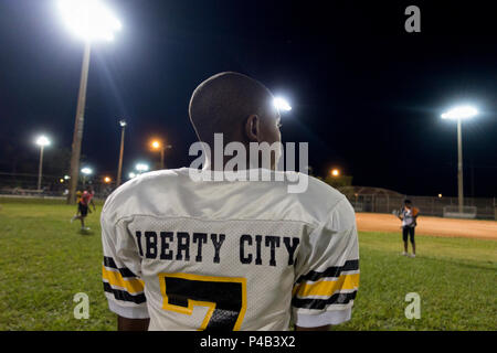 Giovane ragazzo in calcio orologi uniforme i compagni di team play sul campo di notte, Miami, Florida Foto Stock