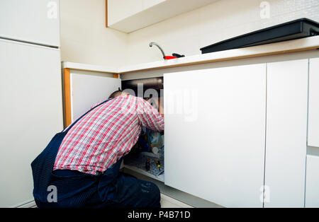 Le riparazioni del lavoratore il problema di perdita nel lavello da cucina Foto Stock